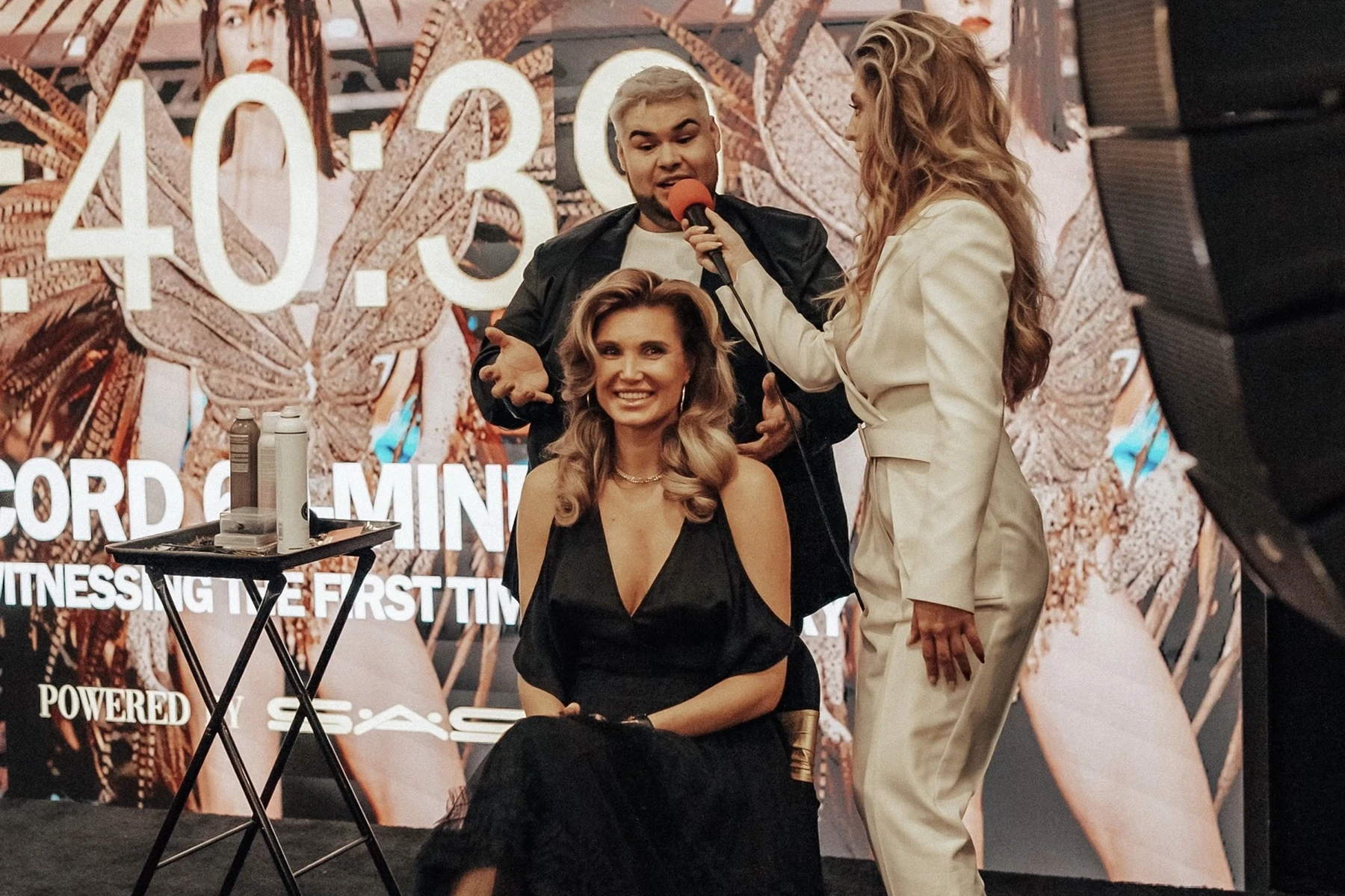 Live beauty event on stage with a host, stylist and model before an audience